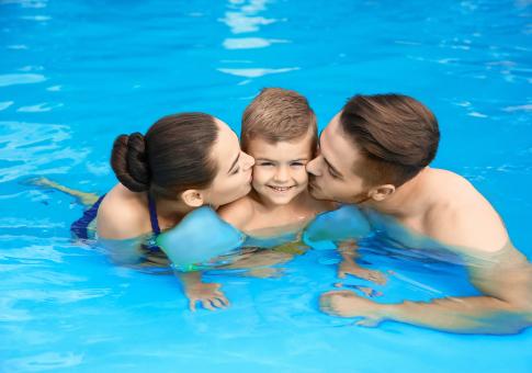 Famiglia felice abbracciata in piscina, sorrisi e amore.