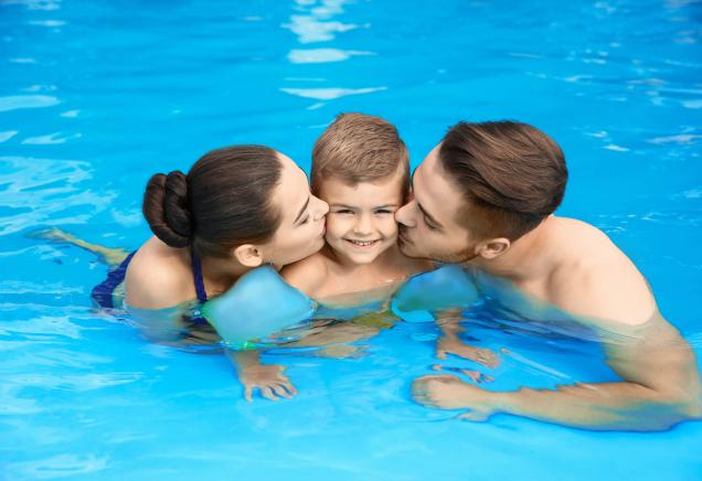 Famiglia felice abbracciata in piscina, sorrisi e amore.